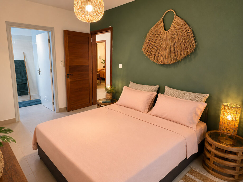 Chambre bohème avec lit double, mur vert, suspension en rotin et décoration naturelle à Villa Zoli Baz, La Preneuse