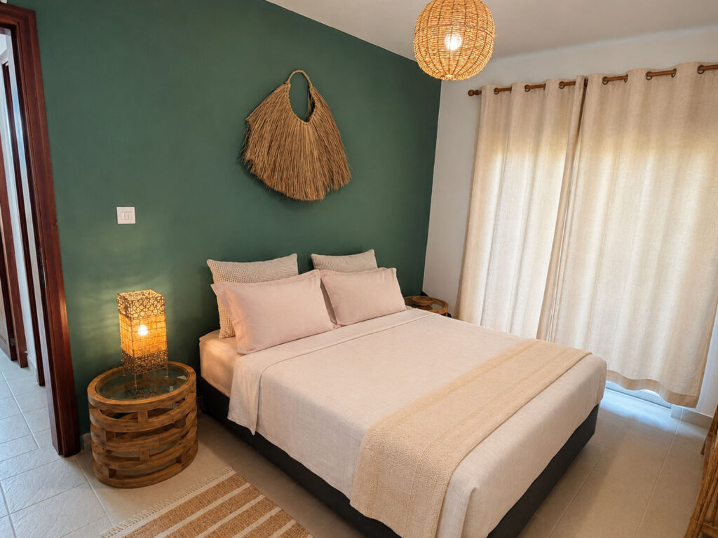 Chambre bohème tropicale avec lit double, mur vert et décoration naturelle à Villa Zoli Baz, La Preneuse