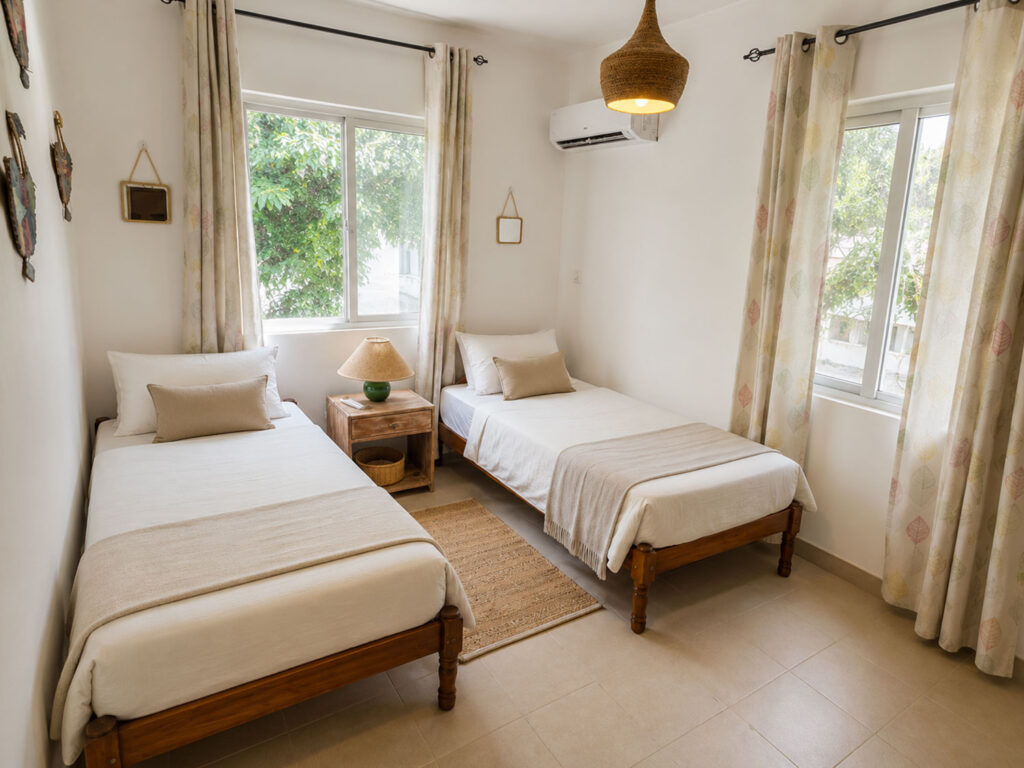 Chambre twin lumineuse avec deux lits simples, fenêtres ouvertes et décoration naturelle à Villa Zoli Baz, La Preneuse