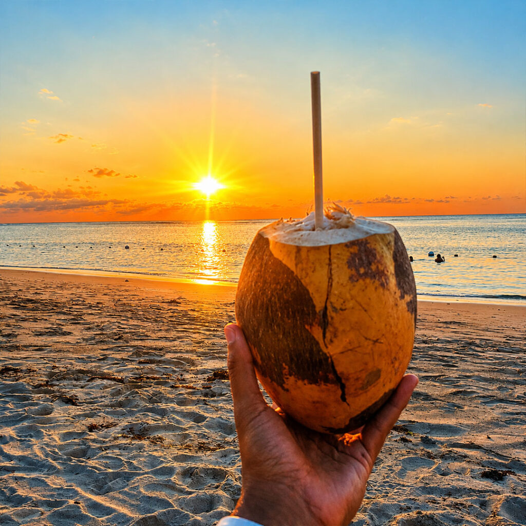 Noix de coco fraîche face au coucher de soleil sur la plage de Flic en Flac à l’île Maurice