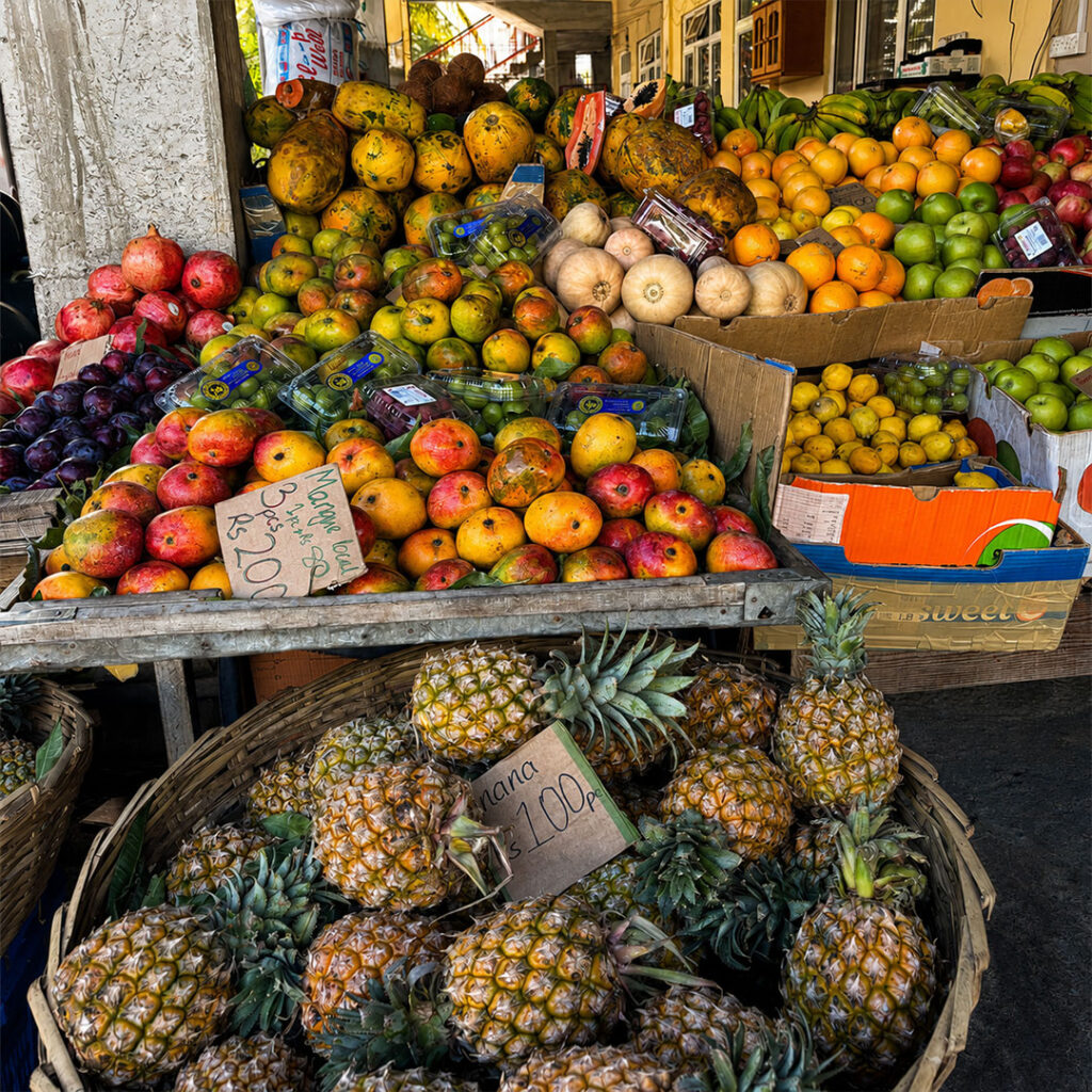 Étal de fruits tropicaux avec ananas, mangues, papayes et agrumes à Flic en Flac, île Maurice